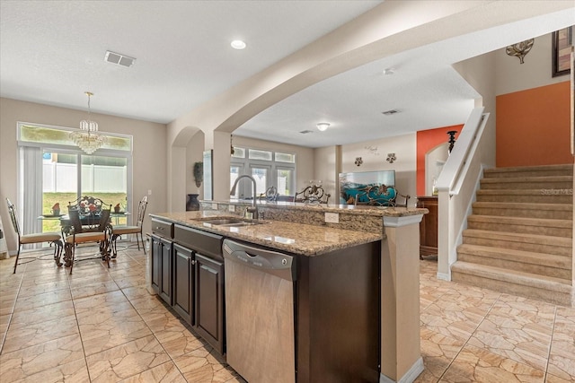 kitchen with light stone counters, plenty of natural light, arched walkways, dishwasher, and a sink