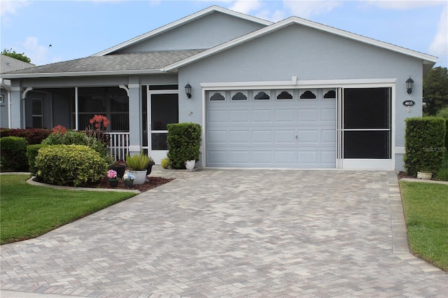 ranch-style home with stucco siding, decorative driveway, a front yard, a garage, and a shingled roof