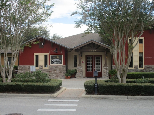 craftsman house featuring french doors, stone siding, and a shingled roof