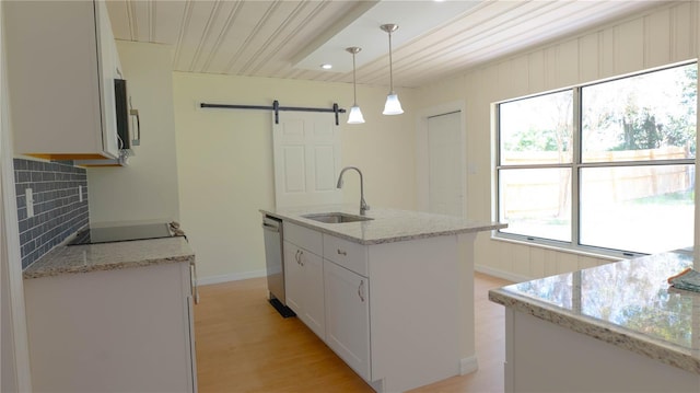 kitchen featuring decorative backsplash, a sink, a barn door, white cabinets, and appliances with stainless steel finishes