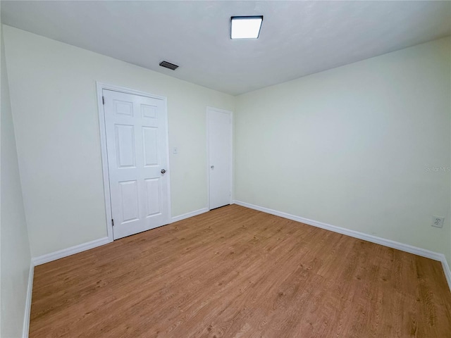 unfurnished room featuring baseboards, visible vents, and light wood-style flooring