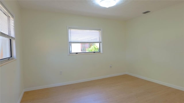 unfurnished room featuring baseboards, visible vents, and light wood finished floors