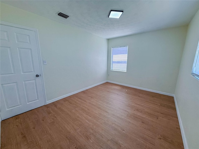 empty room featuring baseboards, visible vents, and wood finished floors