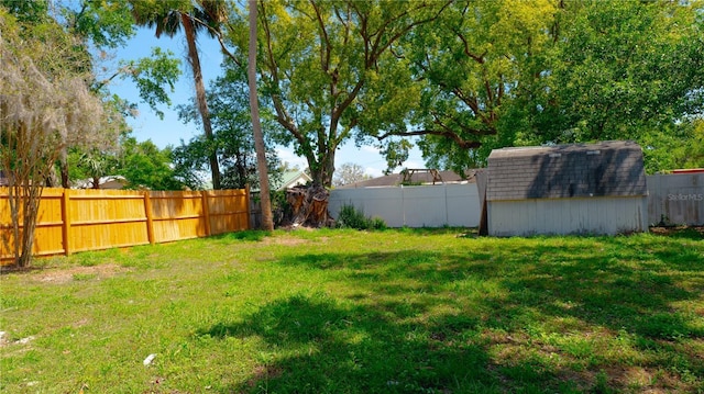 view of yard with an outbuilding, a fenced backyard, and a storage shed