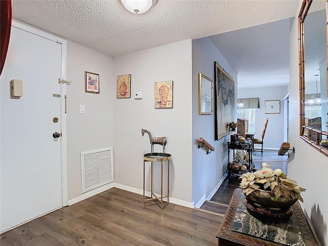 foyer featuring wood finished floors, baseboards, and a textured ceiling