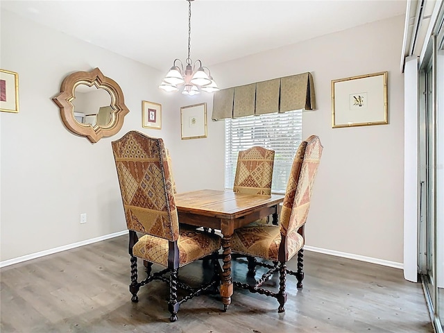 dining space featuring a chandelier, wood finished floors, and baseboards
