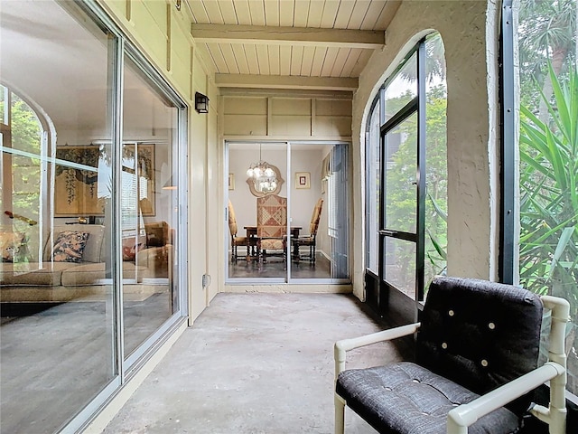 sunroom with a chandelier and beamed ceiling