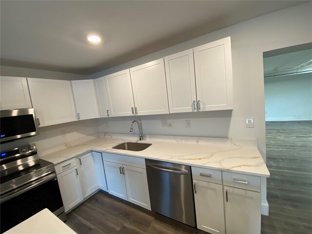 545 Brooks Ct, Polk City, FL 33868 - kitchen with dark wood-type flooring, light stone countertops, appliances with stainless steel finishes, and white cabinets