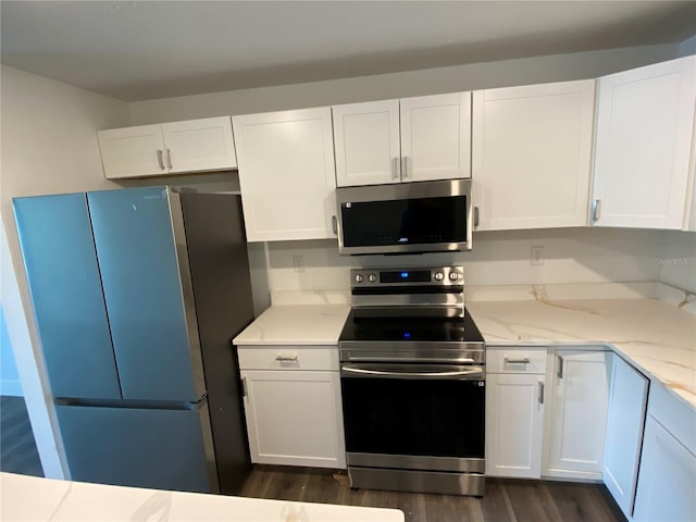 545 Brooks Ct, Polk City, FL 33868 - kitchen with white cabinets, appliances with stainless steel finishes, light stone counters, and dark wood-style floors