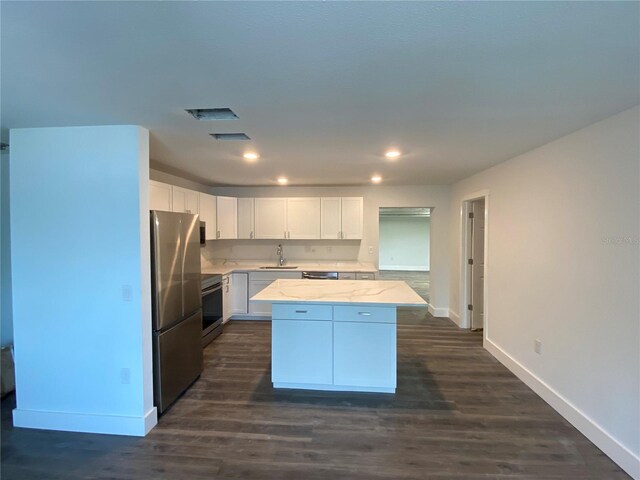 545 Brooks Ct, Polk City, FL 33868 - kitchen with white cabinets, stainless steel appliances, a sink, a center island, and baseboards