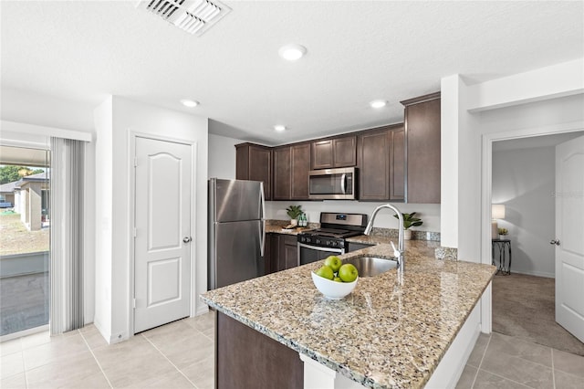 392 Kensington View Dr, Winter Haven, FL 33880 - kitchen with stainless steel appliances, dark brown cabinets, visible vents, light tile patterned flooring, and light stone countertops