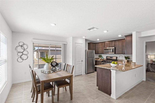 392 Kensington View Dr, Winter Haven, FL 33880 - kitchen featuring stainless steel appliances, visible vents, stone countertops, a sink, and dark brown cabinetry