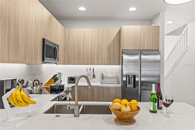 kitchen with light countertops, appliances with stainless steel finishes, modern cabinets, and light brown cabinets