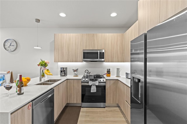 kitchen with appliances with stainless steel finishes, modern cabinets, a sink, a peninsula, and light brown cabinets