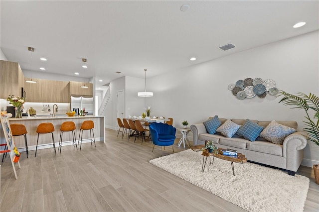 living area with recessed lighting, baseboards, visible vents, and light wood-type flooring