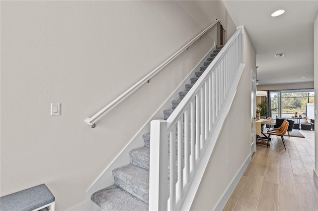 stairway featuring baseboards, recessed lighting, wood finished floors, and visible vents