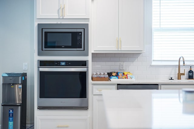 4012 Meandering Bay Dr, Apopka, FL 32712 - kitchen featuring stainless steel appliances, a sink, white cabinets, and decorative backsplash