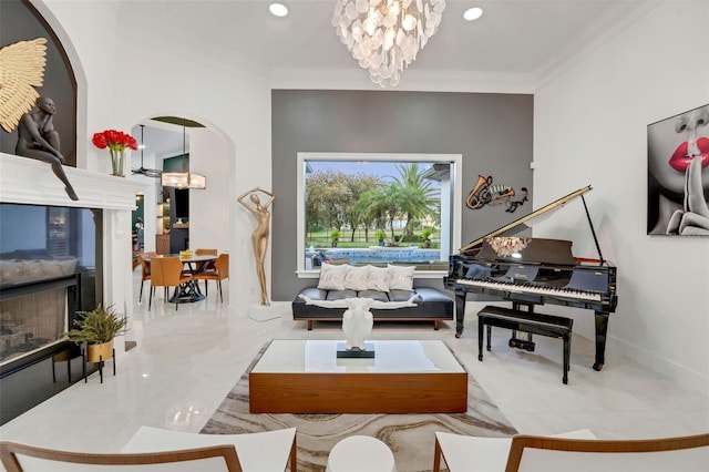 living area featuring a chandelier, arched walkways, baseboards, and ornamental molding