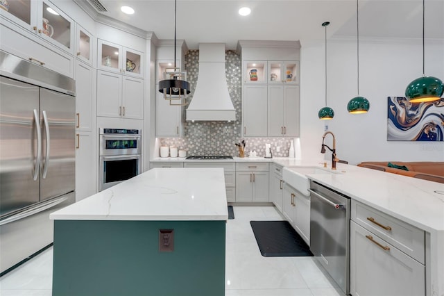 kitchen featuring tasteful backsplash, a peninsula, appliances with stainless steel finishes, a sink, and premium range hood