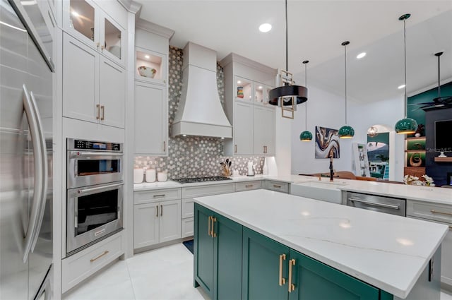 kitchen with green cabinets, appliances with stainless steel finishes, custom range hood, and a kitchen island