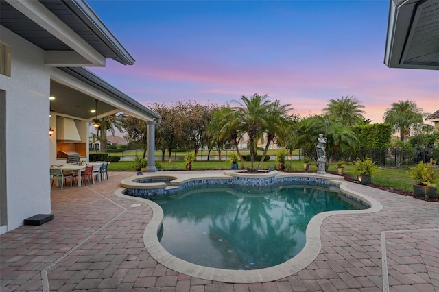 view of swimming pool featuring outdoor dining space, a patio, exterior kitchen, a pool with connected hot tub, and fence