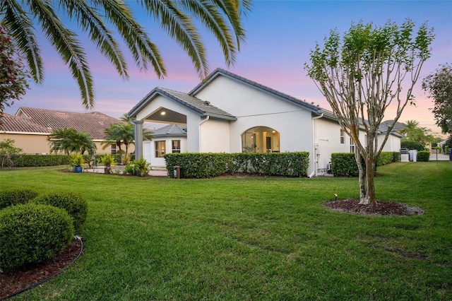 view of front of home featuring a tile roof, a front lawn, and stucco siding