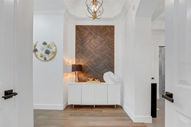corridor with baseboards, wallpapered walls, ornamental molding, an accent wall, and wood finished floors