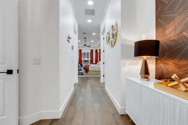 hallway with visible vents, baseboards, crown molding, recessed lighting, and wood finished floors