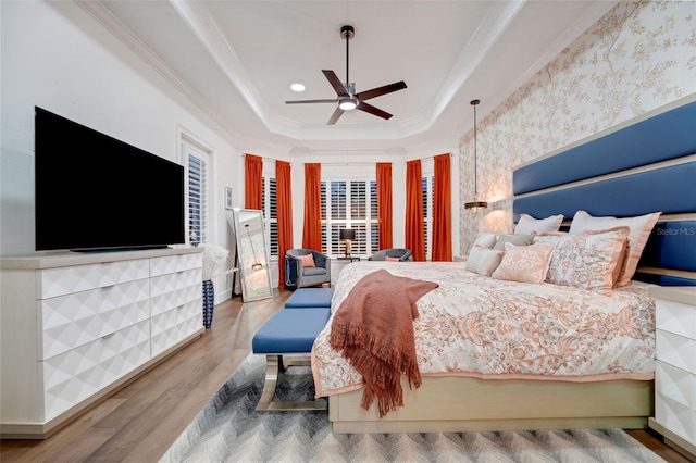 bedroom with crown molding, a tray ceiling, ceiling fan, and wood finished floors