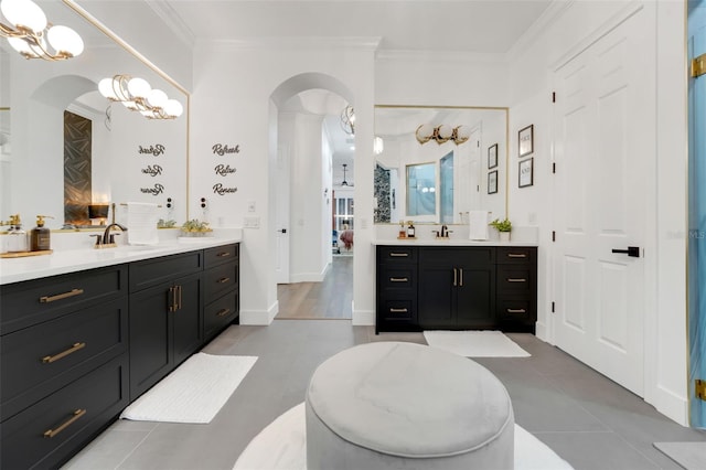 bathroom with crown molding, two vanities, a sink, and tile patterned flooring