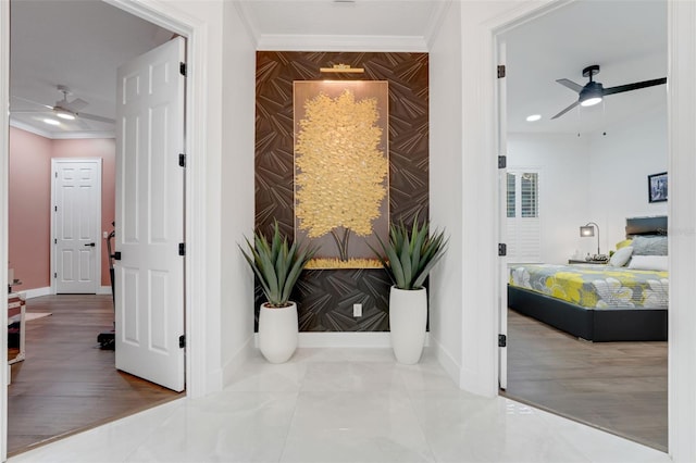 corridor featuring an accent wall, baseboards, and crown molding