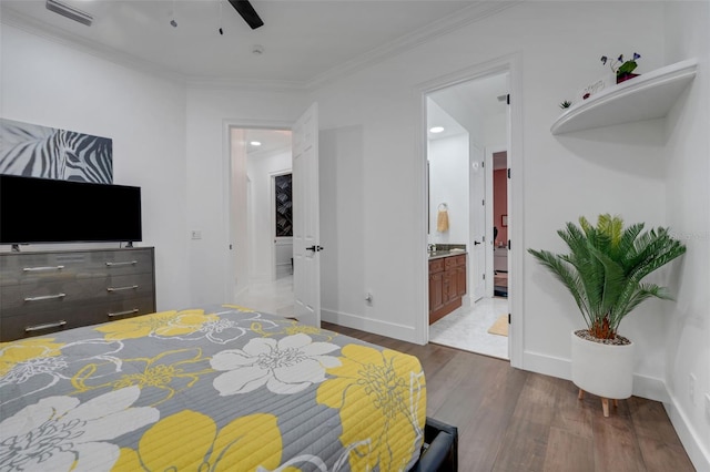 bedroom with ensuite bathroom, ornamental molding, visible vents, wood finished floors, and baseboards