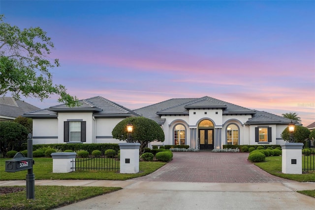 view of front of home featuring french doors, a tile roof, fence, and stucco siding