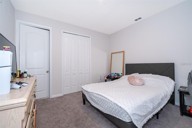 carpeted bedroom featuring visible vents and a closet