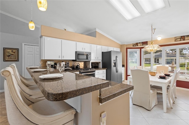 26901 Racquet Cir, Leesburg, FL 34748 - kitchen featuring light tile patterned floors, white cabinets, appliances with stainless steel finishes, a peninsula, and hanging light fixtures