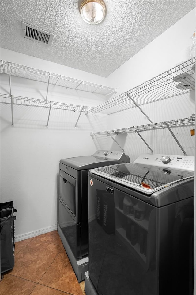 26901 Racquet Cir, Leesburg, FL 34748 - washroom with laundry area, washing machine and clothes dryer, baseboards, visible vents, and a textured ceiling