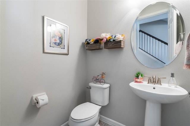 half bathroom with toilet, baseboards, and a sink