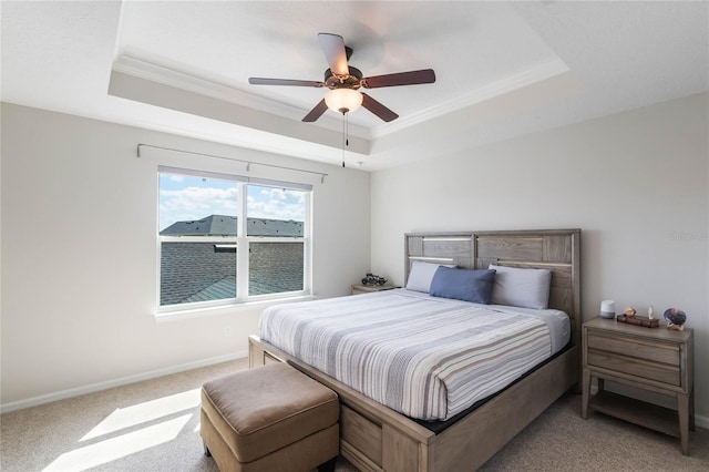 carpeted bedroom with a tray ceiling, ceiling fan, ornamental molding, and baseboards