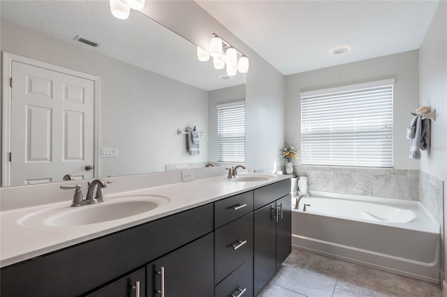bathroom with a sink, double vanity, tile patterned floors, visible vents, and a garden tub