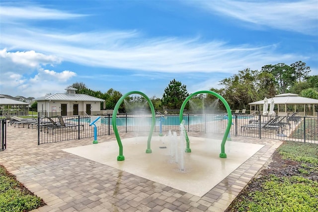 view of playground with a patio, a community pool, fence, and a gazebo