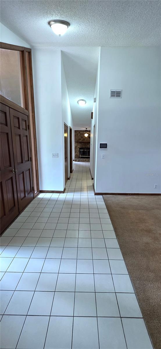 6277 Cranberry Ln W, Jacksonville, FL 32244 - hall featuring a textured ceiling, light tile patterned flooring, and baseboards