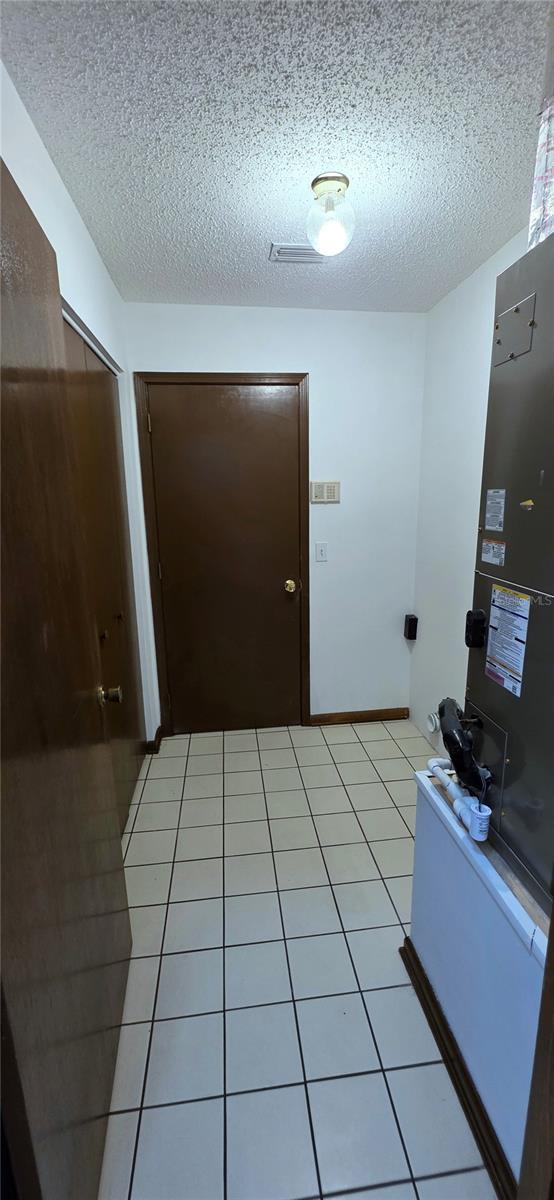 6277 Cranberry Ln W, Jacksonville, FL 32244 - corridor with a textured ceiling and light tile patterned floors