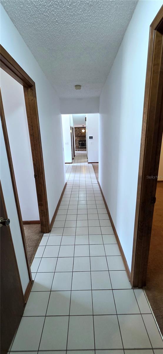 6277 Cranberry Ln W, Jacksonville, FL 32244 - hall with a textured ceiling, light tile patterned floors, and baseboards