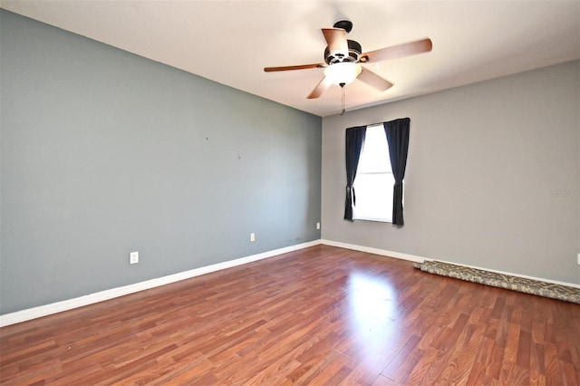 spare room with wood finished floors, baseboards, and a ceiling fan
