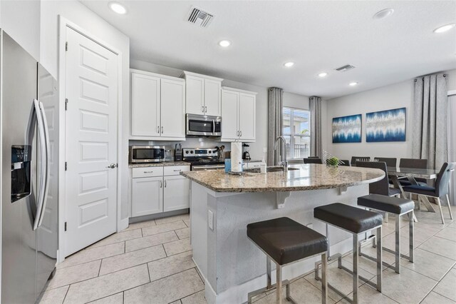 7759 Westland Dr, Kissimmee, FL 34747 - kitchen with light stone counters, appliances with stainless steel finishes, a sink, and visible vents