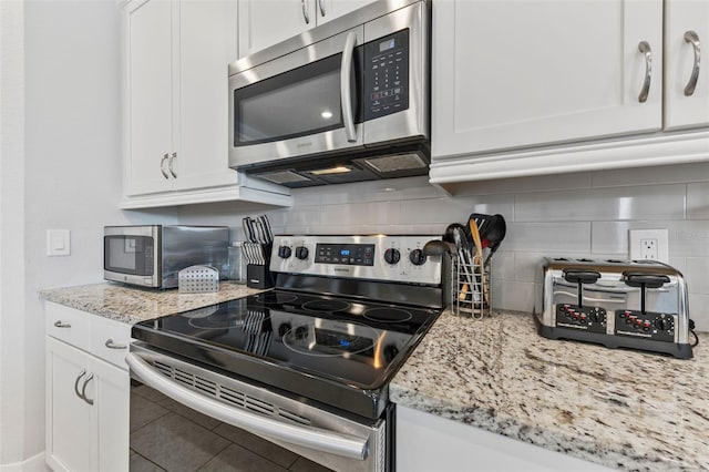 7759 Westland Dr, Kissimmee, FL 34747 - kitchen featuring stainless steel appliances, decorative backsplash, white cabinetry, and light stone counters
