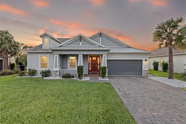 view of front of house with a garage, stucco siding, a porch, decorative driveway, and a standing seam roof