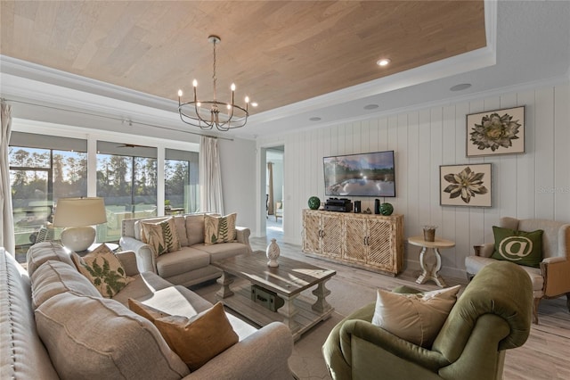 living area with ornamental molding, wood finished floors, recessed lighting, a raised ceiling, and a notable chandelier