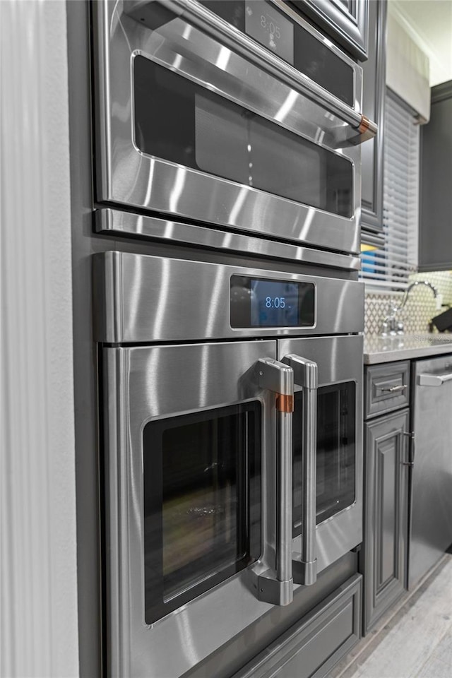 room details featuring decorative backsplash, gray cabinets, dishwasher, and light countertops