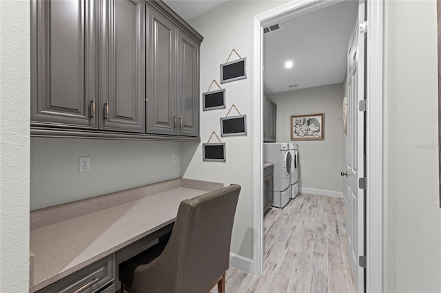 laundry room featuring visible vents, washing machine and clothes dryer, light wood-type flooring, cabinet space, and baseboards